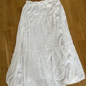 Vit långkjol från Stradivarius - Superfin vit långkjol från Stradivarius med volangdetaljer och resår i midjan. Kjolen är luftig och flowy. Tillverkad i bomull och har en lätt, somrig känsla. 