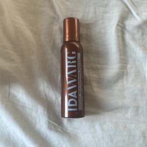 IDAWARG Instant Self-Tanning Mousse - Brun mousse för bus från IDAWARG i en snygg brun och kopparfärgad flaska. Ger en extra mörk solkysst look med tropisk doft. Vegansk formula och enkel att applicera för jämn färg. Endast testad!