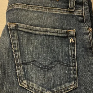 Replay mörkblå jeansbyxor - Säljer ett par mörkblå jeans från Replay med klassisk femficksdesign och snygga detaljer på bakfickan. Jeansen har en stilren look och är tillverkade i slitstarkt denimtyg. Perfekta för dig som gillar en tidlös och cool stil.