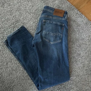 Blå Replay jeans straight fit - Säljer ett par klassiska blå jeans från Replay med raka ben och snyggt sliten tvätt. Jeansen har fem fickor, läderpatch med Replay-logga bak och är tillverkade i mjukt denimtyg. Perfekta för en avslappnad och stilren look.