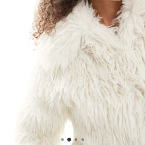 Vit fluffig pälsjacka - Supermjuk och vit pälsjacka med lång luddig fuskpäls. Jackan har hög krage och breda ärmar för en riktigt cozy vibe.