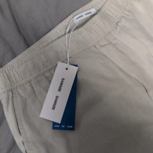 Linnebyxor från Samsøe Samsøe XL - HELT NYA så inga skambud, fick i present men passade ej och glömde lämna tillbaka, oanvända. Snygga ljusa linnebyxor från Samsøe Samsøe i färgen Moonstruck. Byxorna har elastisk midja och raka ben, perfekta för en chill och stilren look. Luftigt material i linne som passar grymt när det är varmt ute.