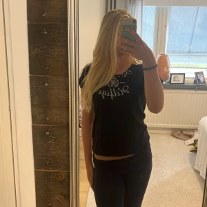 Svart Tommy Hilfiger t-shirt i bomull - Svart t-shirt från Tommy Hilfiger med silverfärgat tryck och logga framtill. Klassisk rund halsringning och korta ärmar. Tillverkad i mjuk bomull, perfekt för en chill och stilren look.