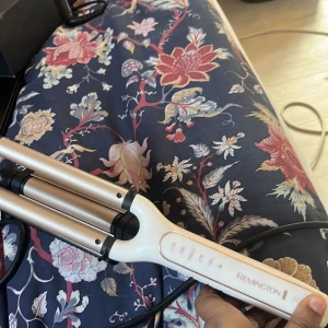 Remington vågtång för håret - Säljer en Remington vågtång i vit och guld med svarta detaljer. Perfekt för att skapa snygga beach waves. Tången har tre cylindrar i metall och ett smidigt handtag med låsfunktion. Sladd medföljer. Enkel att använda för att få volym och struktur.
