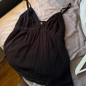 Svart linnetopp med spetsdetaljer - Supersöt svart linnetopp med tunna axelband och v-ringning. Toppen har fina spetsdetaljer längs urringningen och nederkanten💘💘 Använd 1 gång, så inga defekter och nyskick!!☺️Storlek M, men sitter som S.