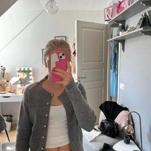 Grå kofta med silvriga knappar från Zara - Mysig grå kofta från Zara med långa ärmar och snygga silvriga knappar framtill. Koftan är stickad och har en klassisk rund halsringning. Koftan är i väldigt bra skick, endast använd fåral gånger. Nypris:299kr