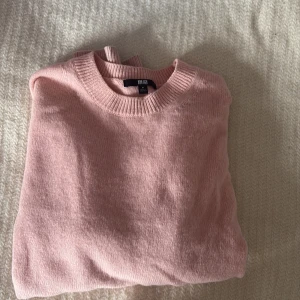 Ljusrosa stickad tröja från Uniqlo - Mysig ljusrosa stickad tröja från Uniqlo med rund halsringning och ribbade muddar. Perfekt för lager-på-lager och enkel att matcha med olika outfits.