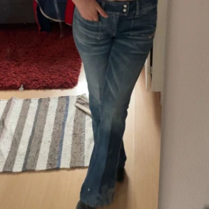 Blå bootcut jeans med dubbla knappar - Snygga blå diesel jeans med bootcut passform och dubbla knappar i midjan