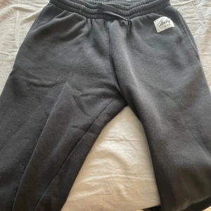 Svarta mjukisbyxor från Andy by Frank Dandy - Svarta mjukisbyxor från Andy by Frank Dandy med resår i midjan och raka ben. Byxorna har en enkel och stilren design utan synliga detaljer och är tillverkade i mjukt material som passar perfekt för en avslappnad stil.