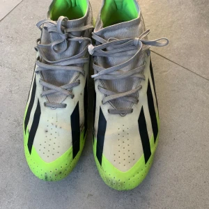 Adidas crazyfast - Säljer ett par Adidas fotbollsskor i vitt med neongula och svarta detaljer. Skorna har snörning och en låg profil, perfekt för snabba rörelser på planen. Insidan är fodrad i neongrönt och ovandelen har klassiska svarta ränder.