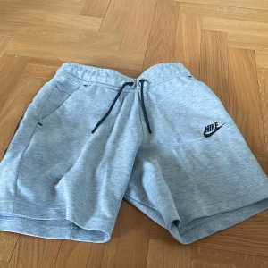 Grå mjuka shorts från Nike - Snygga grå shorts från Nike med svart logga på vänster ben. De har dragsko i midjan och praktiska fickor på sidorna. Perfekta för träning eller chill dagar. Tillverkade i mjuk bomullsblandning för extra komfort.priset är inte fast hör av er vid svarar vanligtvis inom en timme 