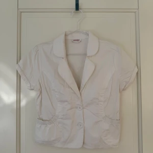 Vit kortärmad topp - Jättesöt topp med små fickor och knappar framtill. Är lite dammig då den hängt på en klädställning, inget som inte kommer gå bort när jag tvättar den. 