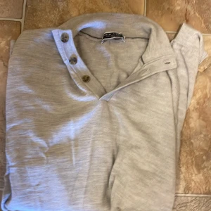 Ljusgrå pikétröja från Charles Tyrwhitt - Säljer en stilren ljusgrå pikétröja / button neck jumper från Charles Tyrwhitt. Tröjan har klassisk krage och tre knappar framtill. Perfekt för en avslappnad men ändå uppklädd look. Materialet känns mjukt och bekvämt mot huden. Extremt skön, skönare än mina tröjor för 4000. Nypris ligger på 1.1, min tröja är helt ny med inga defekter. Aldrig använd, enbart skrynklig för att den legat i garderoben . Köp gärna bundle/ byte