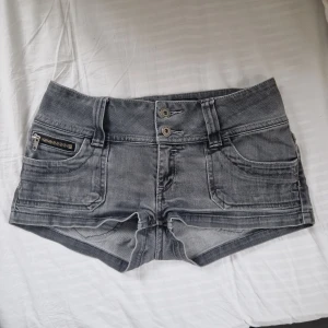 Lågmidjade jeansshorts från ONLY - Säljer nu ett par jätte fina lågmidjade gråa jeansshorts från ONLY med dubbla knappar framtill, har en extra dragkedjedetalj på ena fickan. Shortsen har en lågmidja. Skriv först vid funderingar🩷
