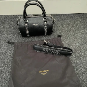 Svart Zadig & Voltaire väska - Svart handväska i skinn från Zadig & Voltaire. Modell: Sunny Logo Plaque XS Tote Bag. Den är i väldigt fint skick, använts ett fåtal gånger men mäst stått i garderoben. Har ett avtagbart axelband och kommer med original dustbag.😊
