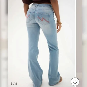 Ljusblå bootcut jeans med broderade bakfickor - Ljusblå low waist jeans med bootcut passform. Bakfickorna har ett broderat zigzag-mönster i rosa. Jeansen har dubbla knappar framtill och klassiska fickor. Dem är endast testade, annars  helt oanvända, men har dock ingen prislapp kvar!