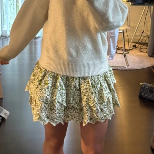  blommig volangkjol - Supersöt kort kjol med volanger och broderade blommor i grönt. Finns inte längre att köpa i affär, perfekt till sommaren🙌🏻☀️endast använd ett fåtal gånger men i super skick!