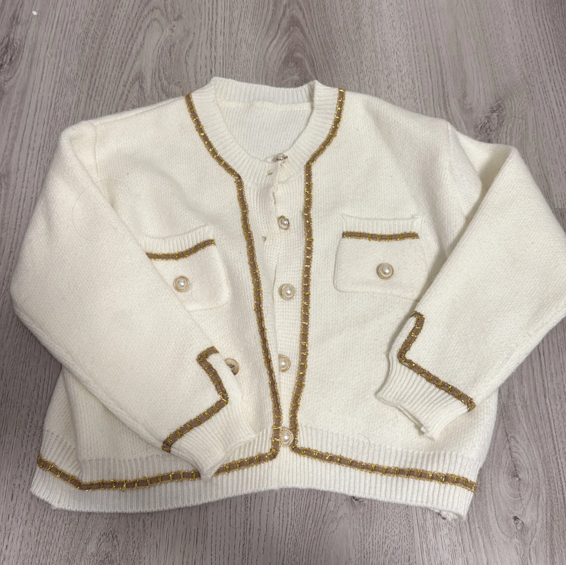 Vit kofta med guldiga detaljer