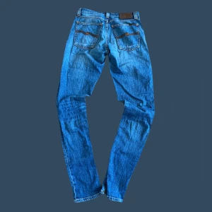 Nudie jeans nyskick - Säljer ett par klassiska blå jeans från Nudie Jeans med deras ikoniska broderade bakfickor. Jeansen har normal passform och raka ben, tillverkade i slitstarkt denim. Perfekta för dig som gillar tidlös stil och bra kvalitet. (Sista bilden är jeansens passform) modellen är ”Lean Dean”) 🔥🙌 w.29 har tyvvär ingen bild med de på eftersom de inte passar mig men de sitter som byxorna på bild 3!🙌
