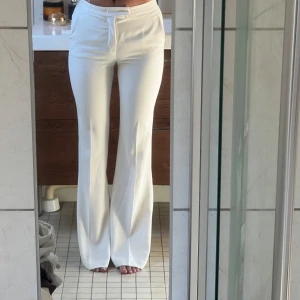 Vita bootcut  kostymbyxor   - Säljer ett par vita byxor med normal passform och utsvängda ben. Byxorna har dragsko i midjan. I storlek 34 men passar även en 36. Inga defekter och känns som ny