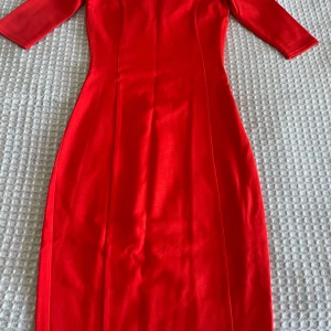 Röd klänning från Mint & Berry - Säljer en snygg vintage röd klänning från Mint & Berry med trekvartsärm och figurnära passform. Klänningen har en klassisk, enkel design och är perfekt för dig som vill sticka ut med färg. Passar lika bra till olika tillfällen.