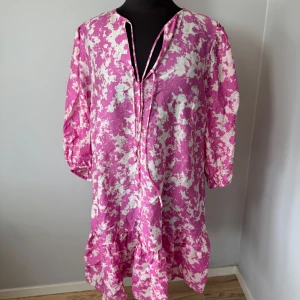 Rosa och vit blommig klänning  - Säljer en luftig rosa och vit blommig klänning från & Other Stories. Klänningen har trekvartsärm, volang nertill och knytning vid halsen. Storlek M men passar även L. Perfekt för sommaren🩷