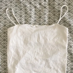 Vit linnetopp med smala axelband - En enkel och stilren vit linnetopp från Gina Tricot med smala axelband. Perfekt för varma dagar och enkel att matcha med olika outfits.