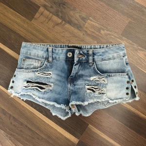 Ljusblå slitna jeansshorts från Mohito - Säljer ett par ljusblå jeansshorts från Mohito med slitna detaljer och fransig kant. Shortsen har nitar på sidorna och klassisk femficksdesign. Perfekta för sommaren och ger en cool, avslappnad look. Inga synliga defekter! För små och har ingen bild med de på heller 💞