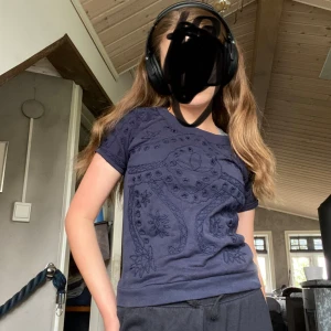 Mörkblå t-shirt med broderi från Juicy Couture - Säljer en mörkblå t-shirt från Juicy Couture med snygga broderade detaljer och blommönster framtill. Står att det är storlek L, MEN är väldigt liten i storlek så skulle säga att det är XS. 