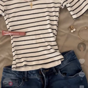 Outfit, Vit ribbad topp och lågmidjade shorts - BILDEN ÄR TAGEN FRÅN MITT TIKTOK KONTO! 🥰Säljer en vit ribbad topp med svarta horisontella ränder, har sytt om för en mer tight look. Shortsen är egentligen jeans från Lindex men har sytt om dom till lågmidjade minishorts💓 