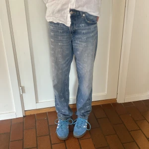 Blå jeans med rosetter River Island - Snygga blå jeans från River Island med raka ben och små diamantrosetter över hela byxan. Klassisk femficksmodell i bomull med normal passform och midja. Perfekta för dig som gillar unika detaljer och en chill stil.