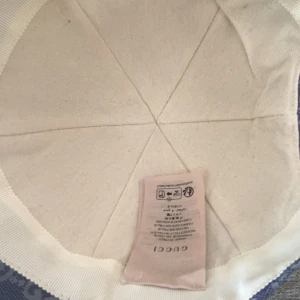 Blå GG-mönstrad keps från Gucci - Snygg blå keps från Gucci i storlek M, täckt av det klassiska GG-monogrammet. Kepsen är tillverkad i bomull och har justerbar rem i blått skinn baktill med gulddetalj. Perfekt för dig som vill sticka ut med en exklusiv accessoar.