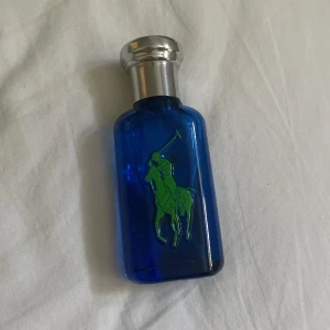 Ralph Lauren big pony  - En snygg parfymflaska från Ralph Lauren big pony med blått glas och silverfärgad kork. Flaskan har den klassiska gröna polospelaren på framsidan. Perfekt för dig som gillar stilrena och sportiga dofter. Nypris ca 500kr. Den är endast använd. Kom gärna med prisförslag eller minsta fundering. 