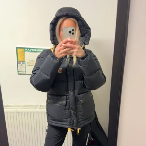 Svart dunjacka från Fjällräven - Säljer den nya svart expedition down lite jacket dunjacka från Fjällräven med huva och gula snören. Inköpt från naturkompaniet för nypris 6999kr! Använd endast en vinter så den är i väldigt bra skick!