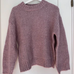 Stickad rosa tröja - Mysig stickad tröja i en ljusrosa/gammelrods nyans perfekt till hösten. Tröjan har en ribbad krage, breda muddar och lång ärm. Jag skulle säga att denna tröjan är lite större i storleken så passar även personer med iallafall storlek XS/S