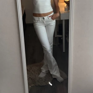 Vita bootcut jeans  - Vita bootcut jeans från Nelly med broderier bak på fickorna! Storlek 34 men passar även mig som har Xs/32 i vissa byxor.  ALDRIG ANVÄNT 