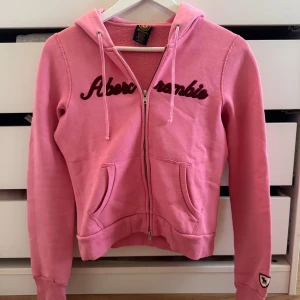 Rosa zip hoodie Abercrombie & Fitch  - Säljer en jättefin rosa zip hoodie ifrån Abercrombie & Fitch i storlek 170 men passar XS!🩷