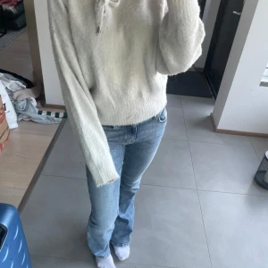Vit fluffig stickad hoodie H&M XS - Supermjuk och fluffig vit stickad hoodie från H&M i storlek XS. Tröjan har långa ärmar, snörning i halsen och en oversized känsla. Perfekt för dig som gillar en cozy och chill vibe under höst och vinter.