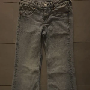 snygga ljus blåa flared jeans från H&M  - Snygga grå jeans med breda ben och hög midja. Klassisk femficksmodell med knapp och dragkedja framtill. Jeansen har en cool tvättad look och raka sömmar längs benen. Perfekta för dig som gillar en avslappnad och trendig stil.