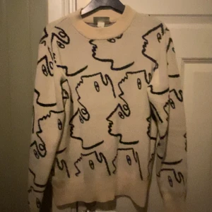 Beige stickad tröja med ansiktsmönster - Beige stickad tröja med motiv på, perfekt till vinter eller höst