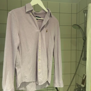 Ljuslila skjorta från Ralph Lauren S - Säljer en ljuslila skjorta från Ralph Lauren i klassisk oxfordstil. Skjortan har lång ärm, knappar framtill och den ikoniska broderade loggan på bröstet. Tillverkad i bomull och passar perfekt för en clean och stilren look.