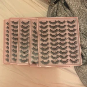 Flera set lösögonfransar i svart - Säljer fem stora förpackningar med dramatiska svarta lösögonfransar. Fransarna är täta, långa och har en snygg volym för en intensiv blick. Perfekta för att skapa en bold look. Kommer i rosa plastaskar, varje ask innehåller flera par.