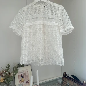 Vit spetsblus från Zara Woman - Superfin vit blus från Zara Woman med genombruten spets,  och korta ärmar. Blusen har vackra broderade detaljer och en lätt volangkant vid ärmslut och hals.