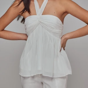 Vit slutsåld topp från Nelly - Supersöt vit topp från Nelly med halterneck och twistad detalj framtill. Tunt, flowy tyg som ger en luftig känsla och snyggt fall. Perfekt till sommarens alla tillfällen när du vill känna dig extra fräsch och chic. Kan ha små sminkfläckar men går bort i tvätten. Kan diskutera pris!