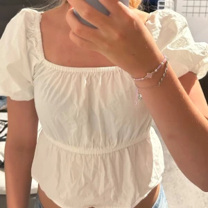 Vit blus med puffärm från Bik Bok - Supersöt vit blus från Bik Bok med puffiga korta ärmar och fyrkantig urringning. Modellen har resår i midjan och vid halsen för en snygg passform. Använd en gång!💗💕