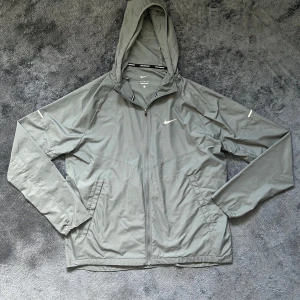 Grå Nike miler windbreaker - Snygg och bra windbreaker. Säljer pga den passar inte mig. Använd några gånger bara
