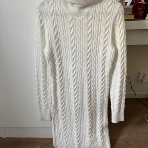 Vit stickad klänning  - Supermysig vit stickad klänning från FB Sister med kabelstickat mönster och polokrage. Långärmad och med ribbade muddar, perfekt för kyliga dagar. Snygg och enkel att styla med boots eller sneakers.