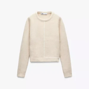 Beige stickad tröja från Zara - Beige stickad tröja från Zara med rund halsringning och lång ärm. Tröjan har en clean look med en diskret vit söm framtill som detalj. Perfekt för dig som gillar en enkel och stilren vibe.