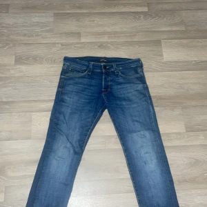 Blå jeans från Jack & Jones - Snygga blå jeans från Jack & Jones med klassisk femficksdesign och diskreta slitningar. Jeansen har raka ben och normal passform, tillverkade i mjukt bomullstyg med lite stretch för extra komfort. Perfekta till sneakers och hoodie.