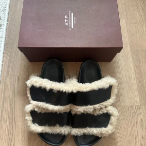 Svarta tofflor från ATP Atelier - Fluffiga tofflor från ATP Atelier. Endast använda utomhus en gång. Som helt nya + orginalkartong. Säljer pga för små🥲 Köpta för 3599 kr. 